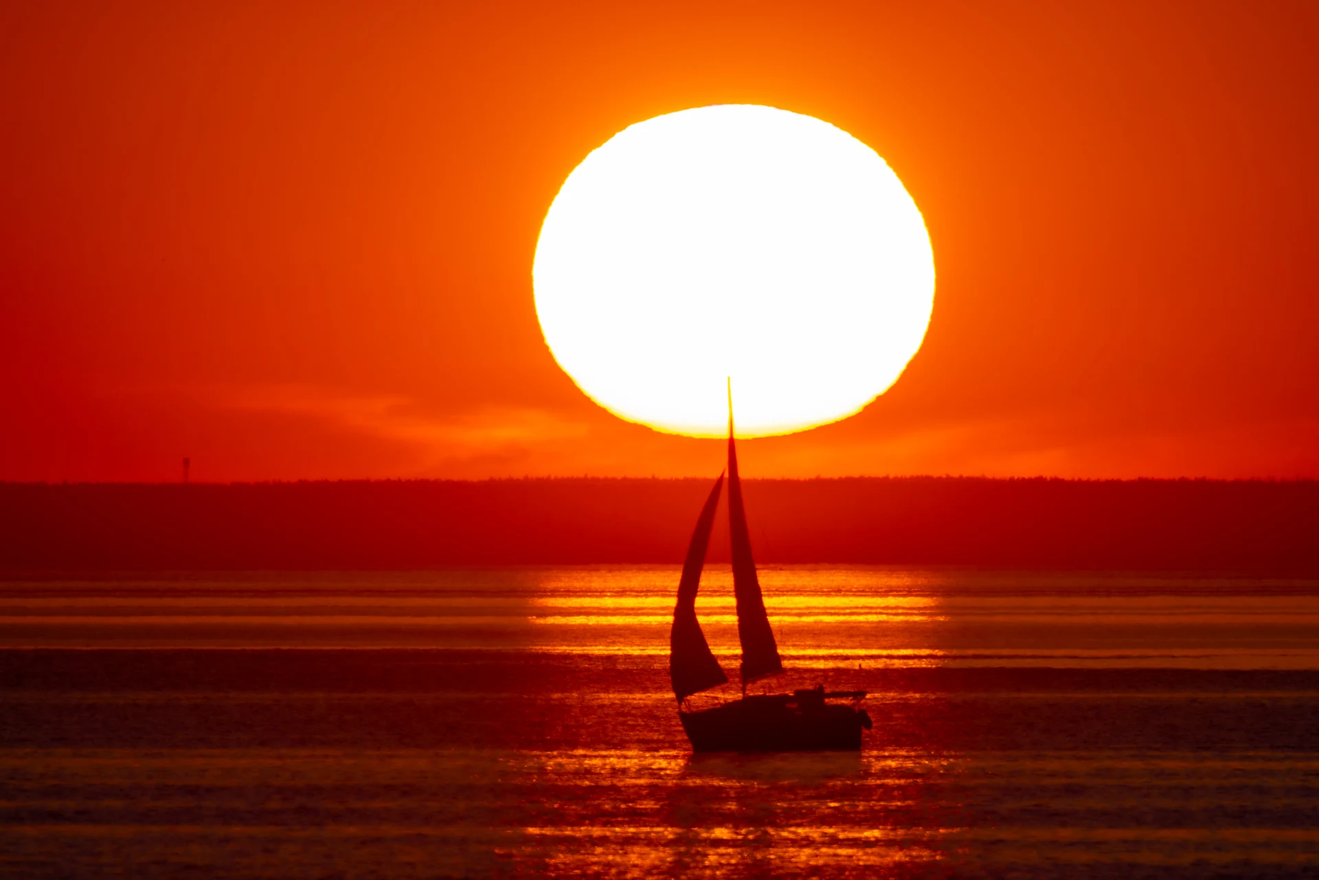 Sailing yacht crossing the sunset, photographed at 1200 mm